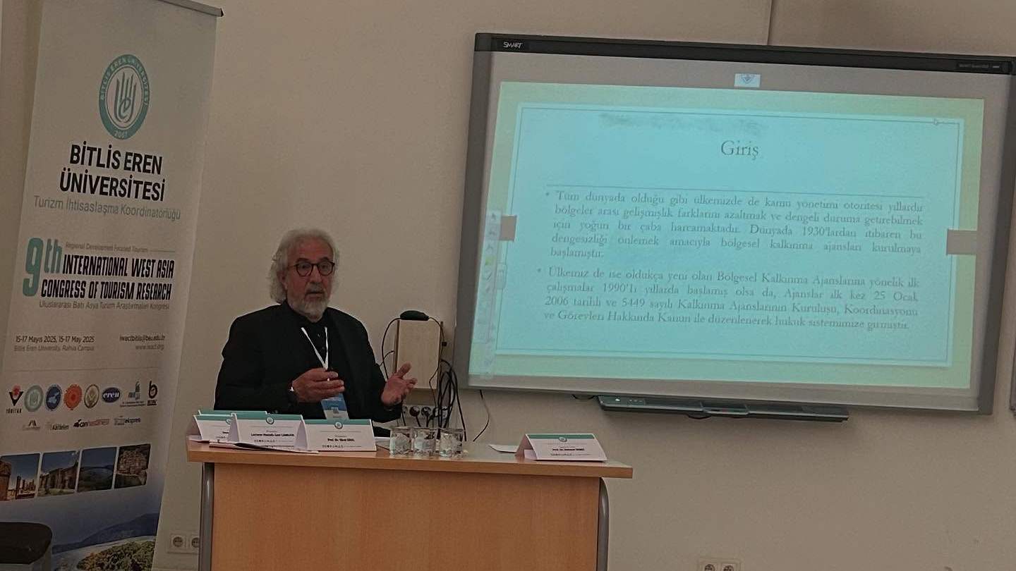 Prof. Dr. Yücel Erol, kongrede bildiri sunarken; arkada sunum ekranı ve kongre afişi